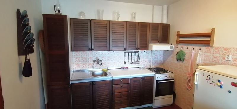 A kitchen in a family house with wooden cabinets and a tiled wall.