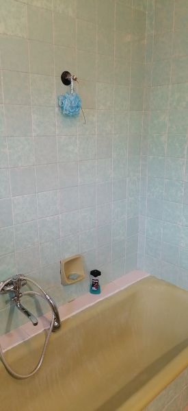 A bathroom in a family house with beige tiles and a bathtub.