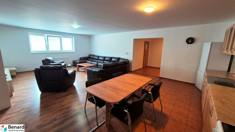 Living room with sofas, a table, a kitchen unit, and a wooden decor floor in a 3-room apartment.