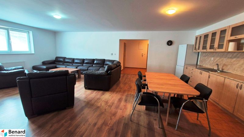 Living room with a sofa, dining table, and kitchen unit in a three-room apartment.
