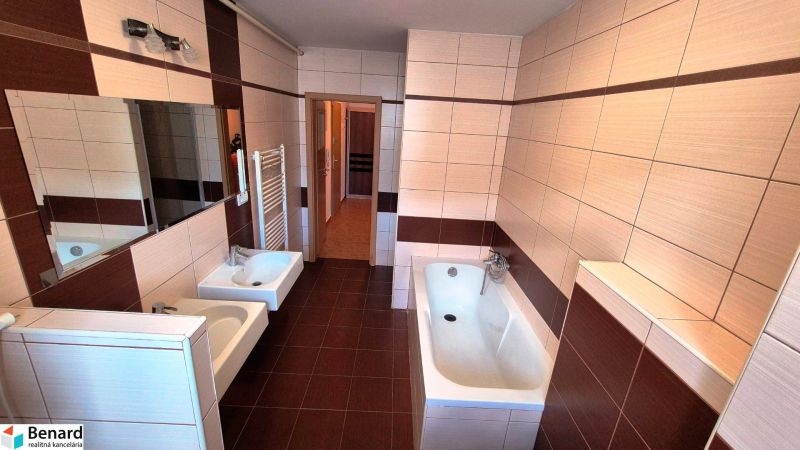 A bathroom in a 3-room apartment with a bathtub, a sink, and ceramic tiles.