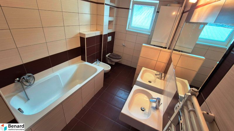 A bathroom in a 3-room apartment with two sinks, a bathtub, and modern tiles.