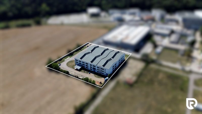 Warehouses and halls on K výstavisku Street in Trenčín, surrounded by greenery and fields.