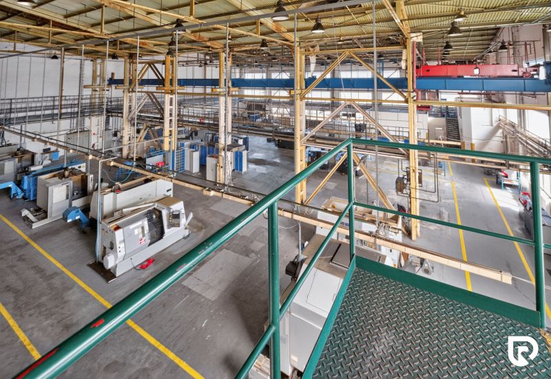 A production hall with a number of machines, a staircase, and a steel structure in warehouses and halls.