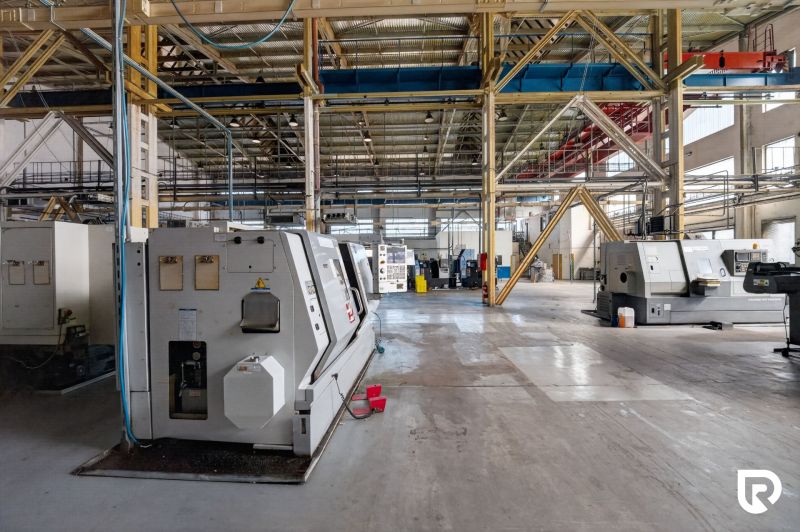 A large hall in a warehouse with industrial machines and a floor with a wooden decor.