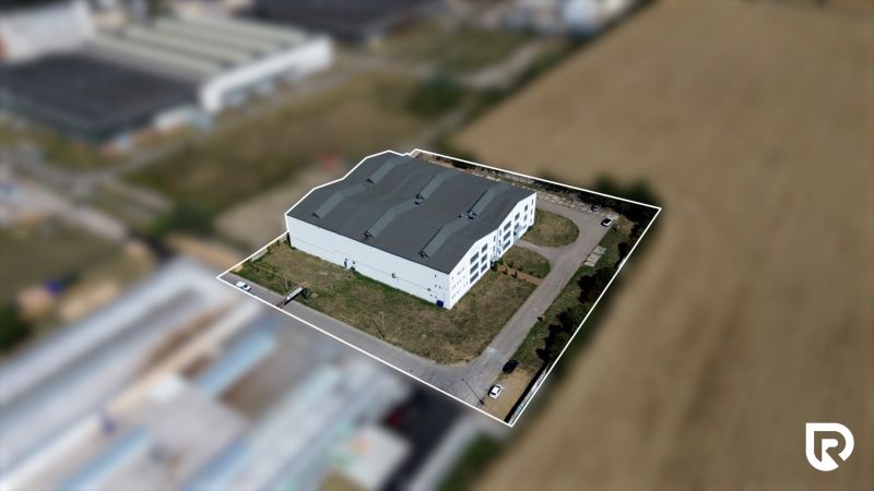 A view of the warehouse in Trenčín on K výstavisku Street, surrounded by a field and a parking lot.