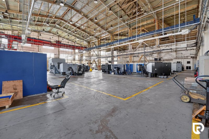 Space warehouses and halls with production machines and a metal roof structure.