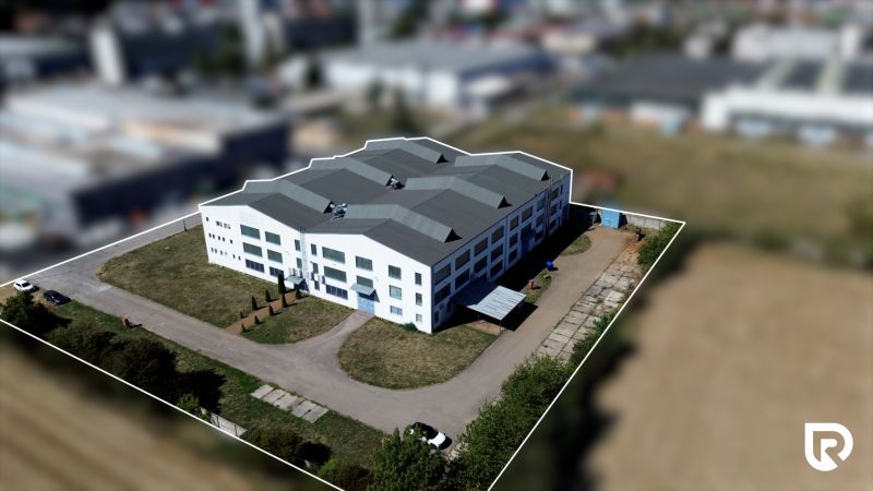 White industrial building in the area of Trenčín, K výstavisku street, surrounded by greenery.