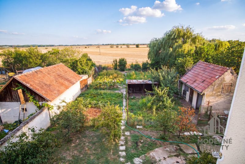 The garden of a family house in Dvory nad Žitavou with a shelter and a view of the fields.