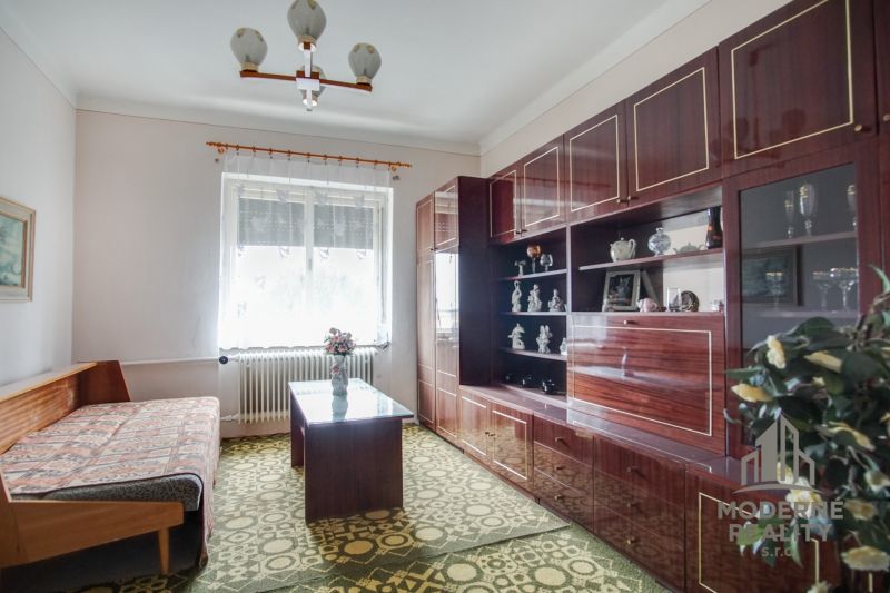 Living room in a family house with a sofa, display cabinet, and carpet.