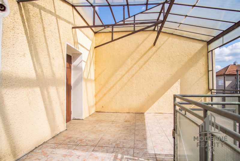 Covered terrace in a family house in Dvory nad Žitavou, with tiles and metal railing.