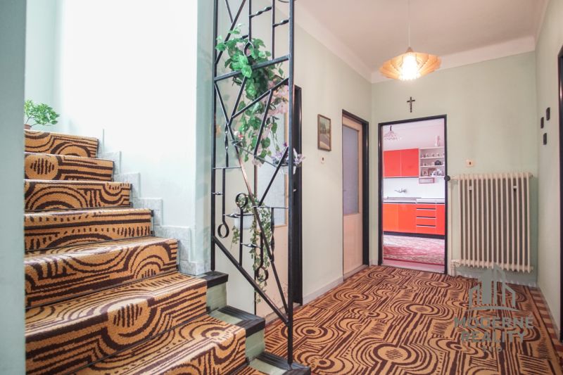 A hallway with a staircase and colorful kitchen doors in a family house.