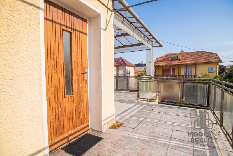 The terrace of a family house in Dvory nad Žitavou with wooden doors and glass railings.