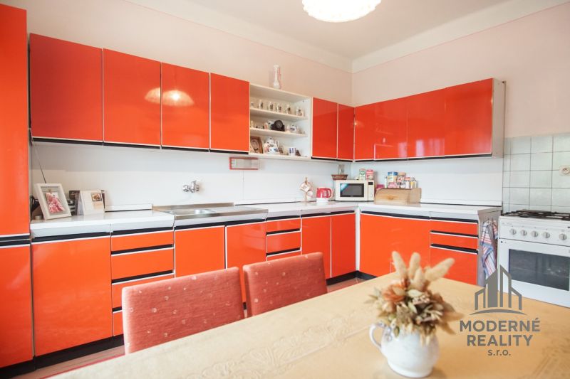 A kitchen in a family house with red cabinets and a dining table.