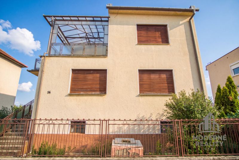 A family house in Dvory nad Žitavou with closed shutters and a glass canopy.
