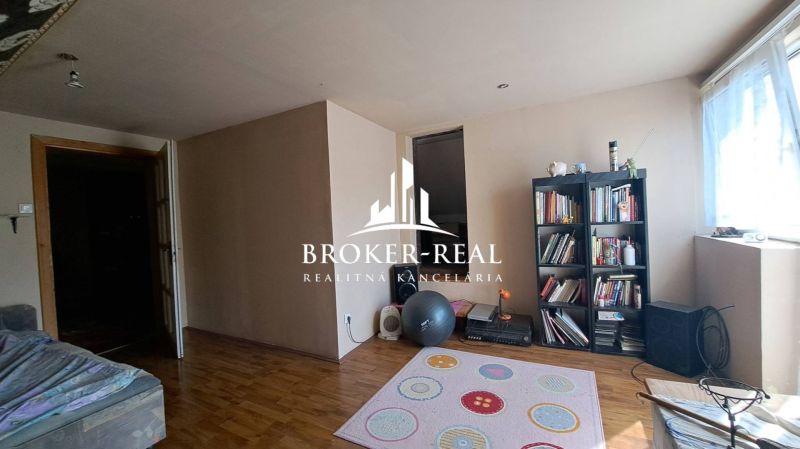 Living room in a cottage with a wooden decor floor and a bookshelf.