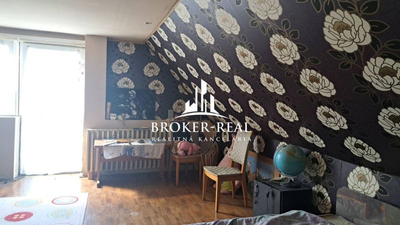 The interior of the cottage with floral wallpaper and a wooden decor floor.