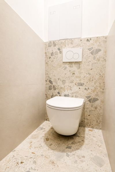 A toilet in a 3-room apartment with stone cladding and a fresh design.