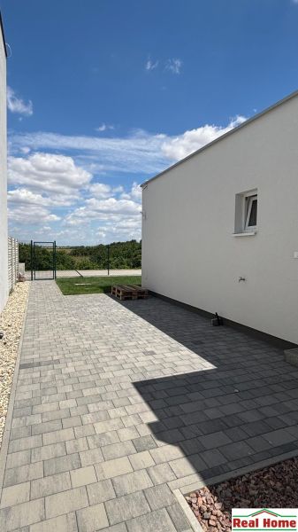 A family house in Boldog with paving, a white facade, and a closed courtyard.