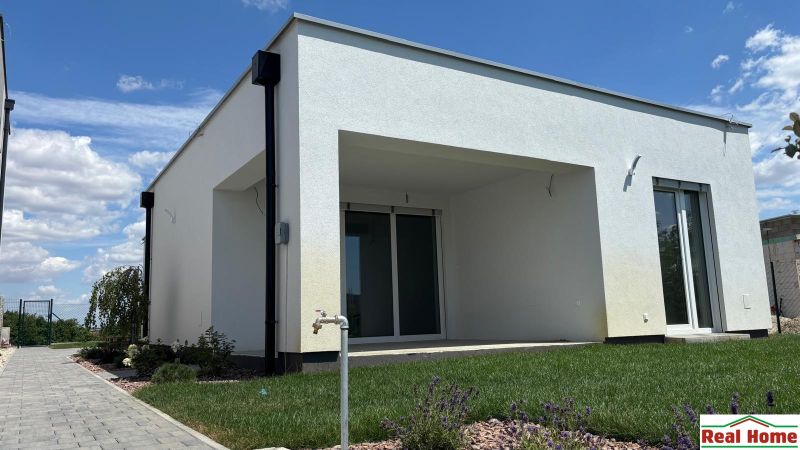 A family house in Boldog with a terrace and a landscaped garden, with a view of the blue sky.