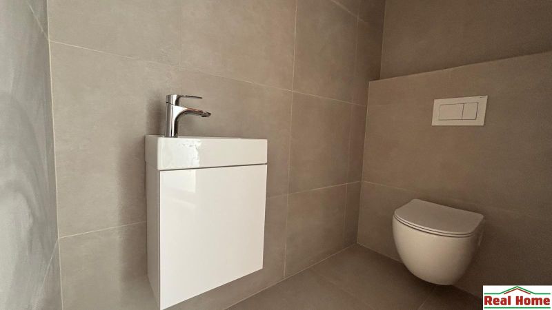 Toilet and sink with walls in neutral shades in a family house.