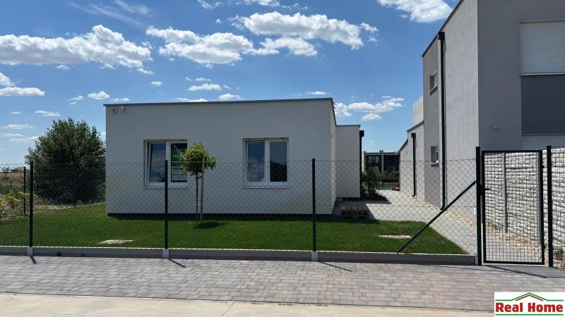 A family house in Boldog with a white facade, garden, and fence.