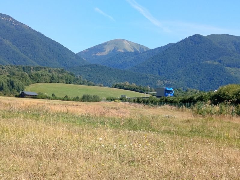 Recreational lands near the town of Turany with a mountain range and a truck on the road.