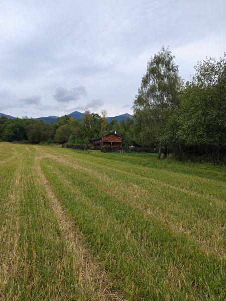 Recreational land in Turany with a wooden cottage, surrounded by nature and mountains.