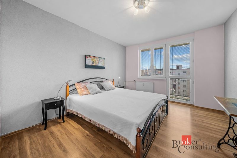 Bedroom with a double bed in a 3-room apartment, wooden decor flooring, bright room.