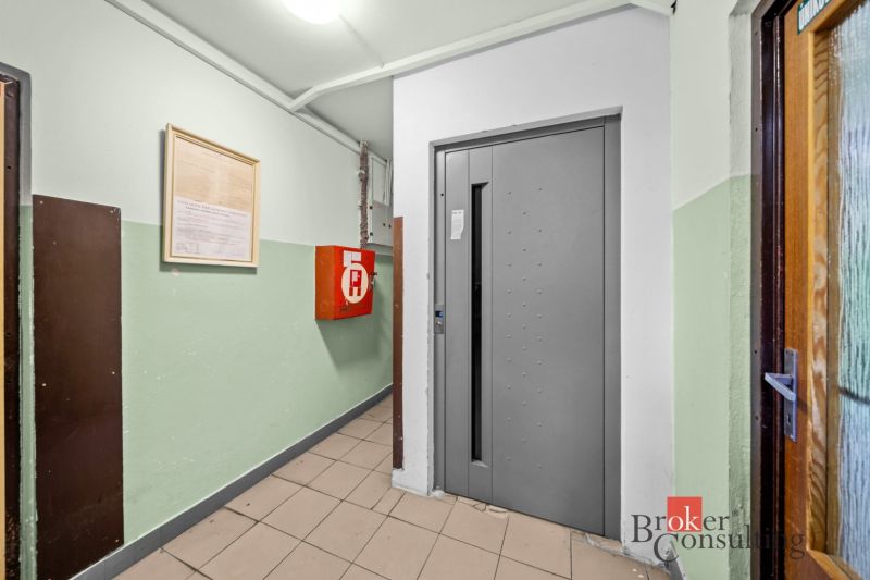 Elevator in the hallway of an apartment building, next to it is a fire cabinet.