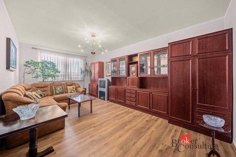 Living room with a sofa set, wooden decor flooring, large display cabinet, 3-room apartment.