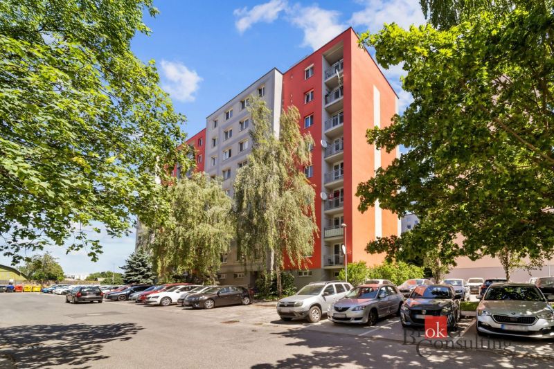 An apartment building on E. F. Scherer Street in Piešťany, surrounded by greenery and parked cars.