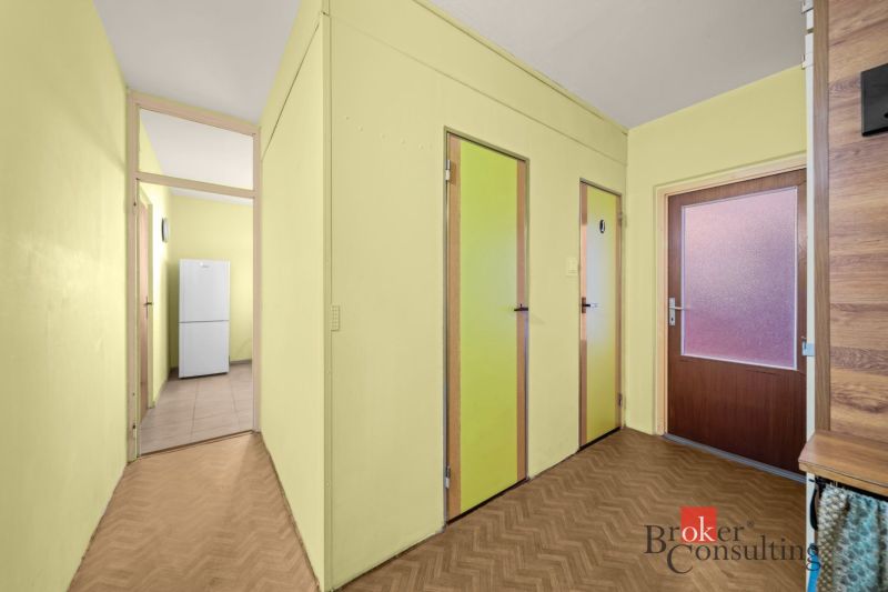 Hallway in a 3-room apartment with a refrigerator, wood-patterned flooring, and yellow walls.