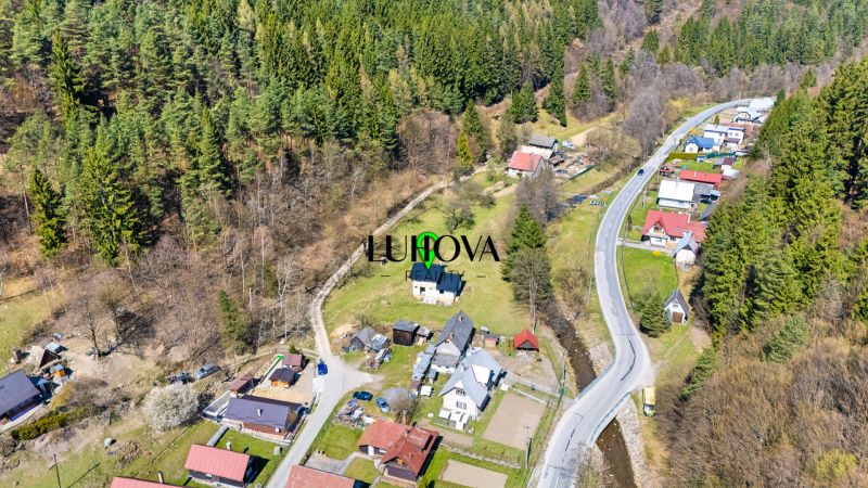 An aerial view of family houses in Lazy pod Makytou surrounded by forests and a road.