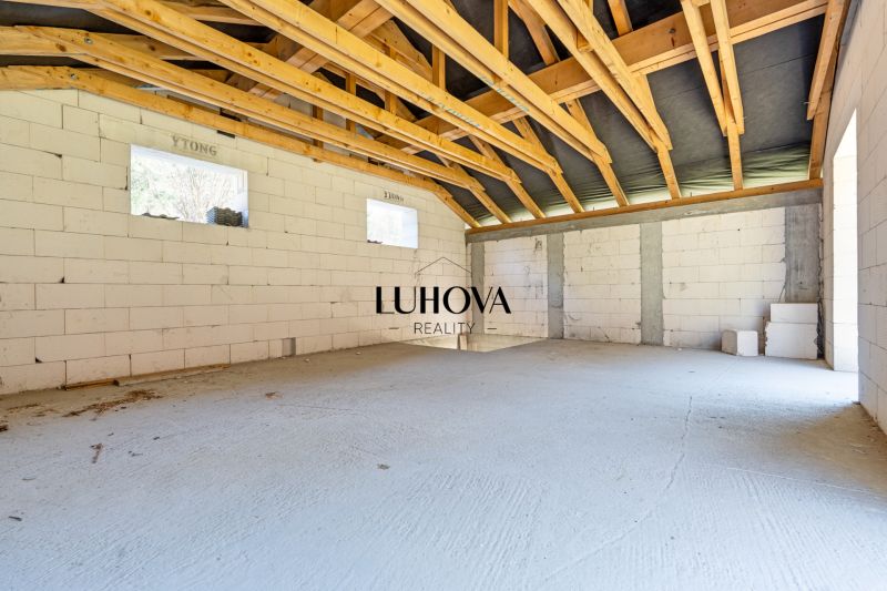 The interior of an unfinished family house with white walls and wooden beams.