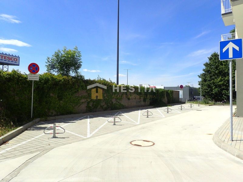 Parking lot by a 3-room apartment in Senica, with traffic signs and fencing.