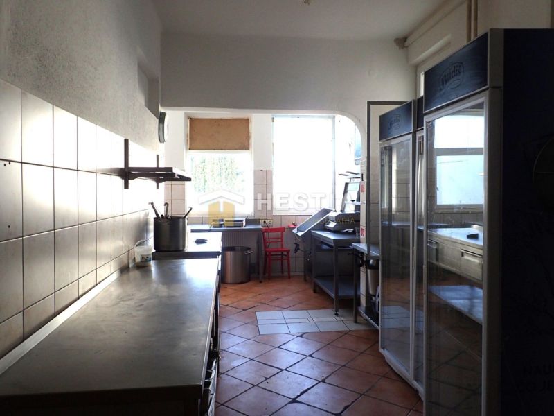 A kitchen in commercial premises with tiles and equipment.