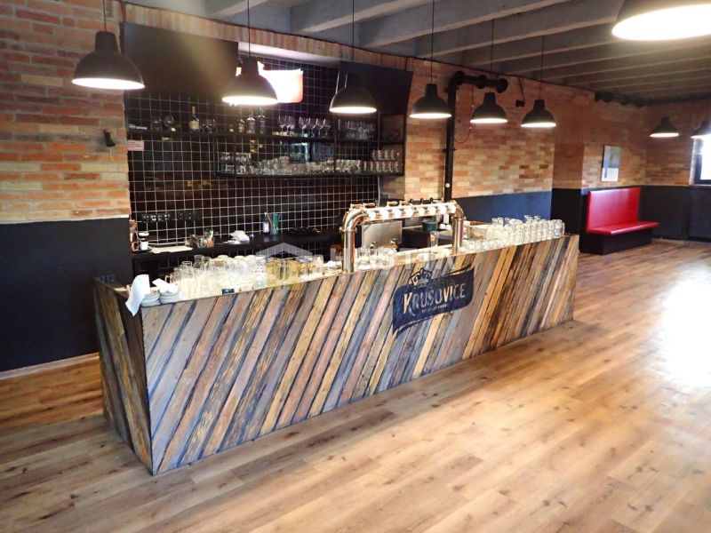 A bar counter in commercial premises with a wooden decor floor and a brick wall.