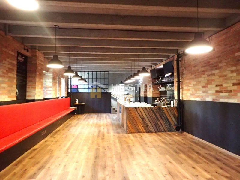 Commercial space with brick walls, a red bench, and a wood-patterned floor.