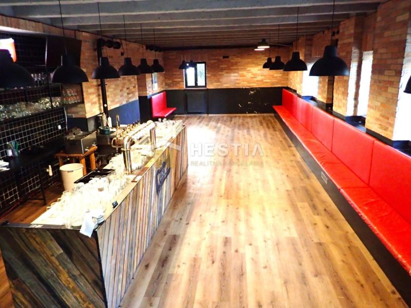 Commercial space with a bar and benches, wooden decor flooring, brick interior.