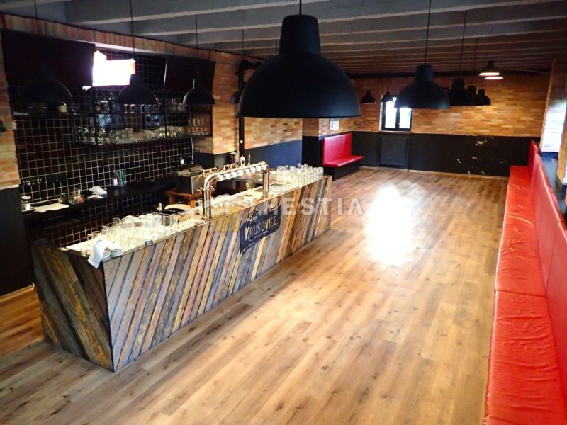 Commercial premises with a bar and wood-patterned flooring, red seating.