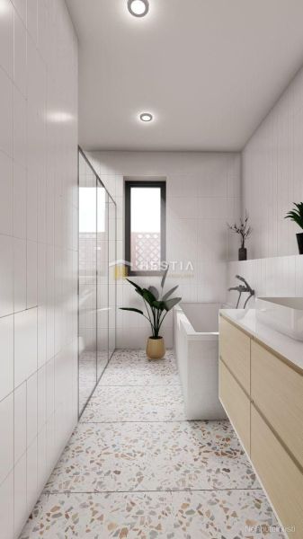 Bathroom in a family house with a bathtub, a plant, and patterned flooring.
