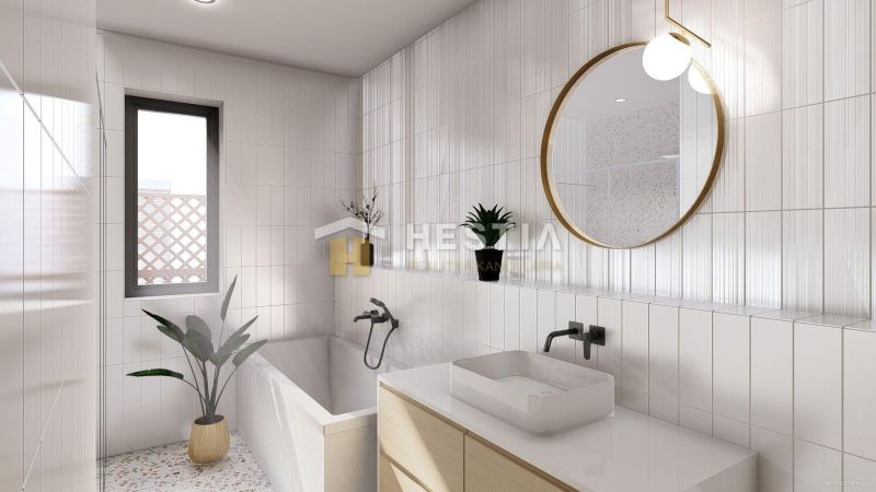 Bathroom in a family house with a bathtub, window, plant, and round mirror.
