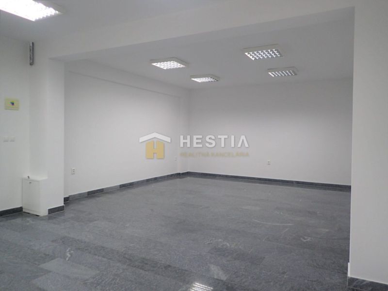 An empty commercial space with wood-patterned flooring and white walls.