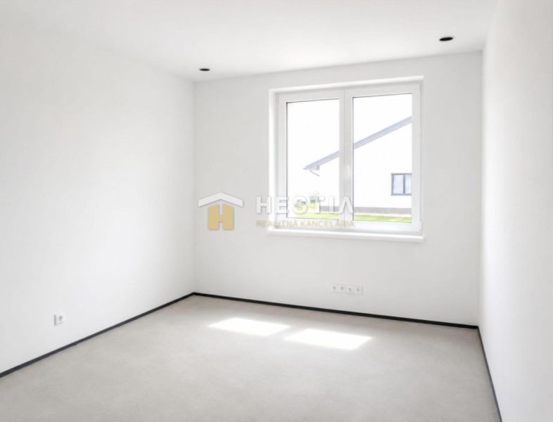 An empty room in a family house with white walls and a floor-to-ceiling window.