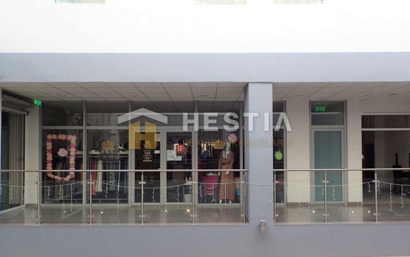 A glass facade of a shop with a display and clothing in a shopping center in Senica.