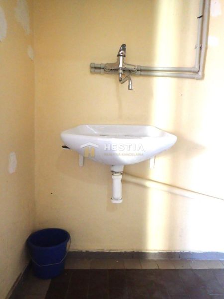 A sink with a blue bucket in the bathroom of a family house.