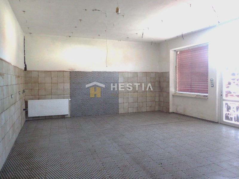 Empty room with tiles, radiator, and large window in a family house.