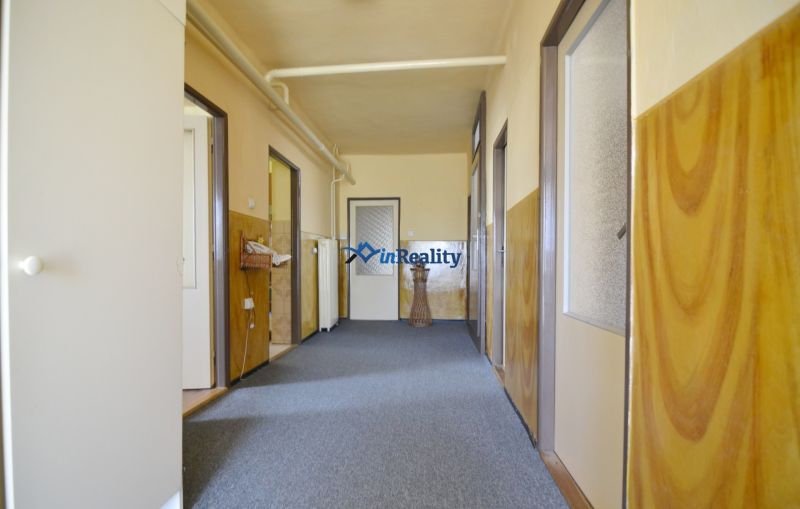 A hallway with light walls and a gray carpet in a family house.