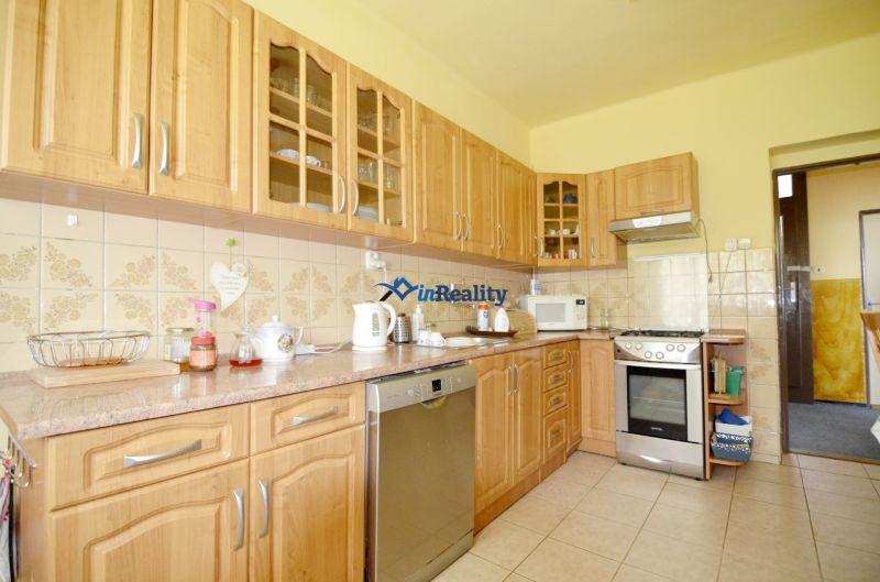 A kitchen in a family house with wooden cabinets, an oven, and appliances.